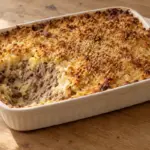 Le parmentier de canard façon grand-mère mêle purée, viande effilochée et légumes sous une croûte dorée, sans couches distinctes.